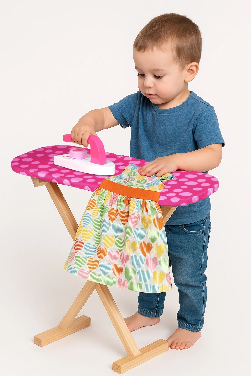Niño pequeño planchando con la plancha de juguete sobre la tabla