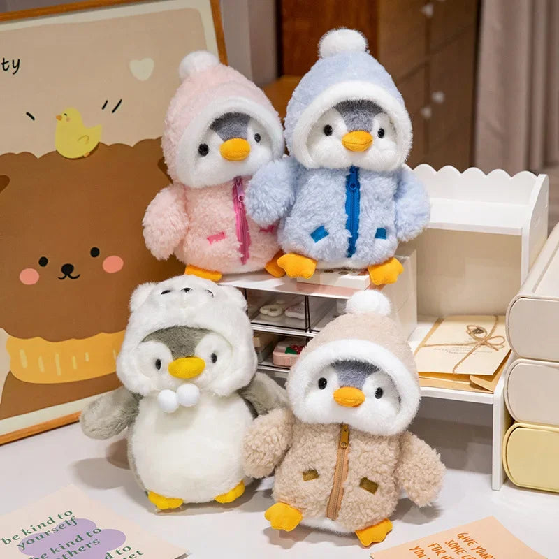 Pingüinos de peluche con abrigos marrón, azul y rosa