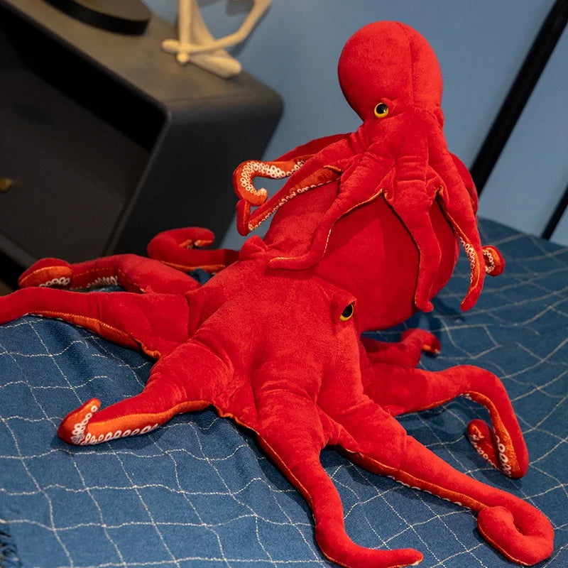 Dos pulpos rojos de peluche sobre una cama