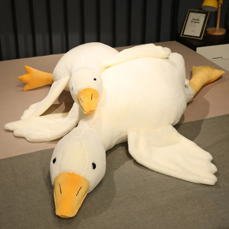 Oca de peluche blanca tumbada con las alas abiertas