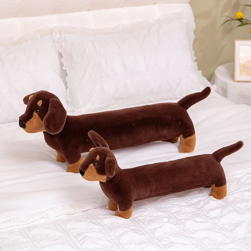 Perros salchicha de peluche de dos tamaños sobre una cama