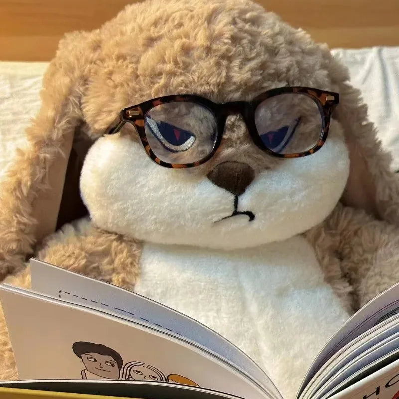 Conejo gruñón de peluche con gafas leyendo un libro