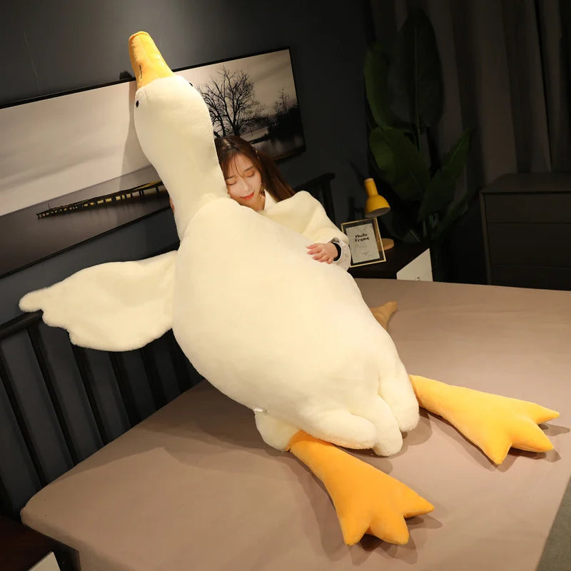 Oca de peluche blanca gigante sentada en una cama